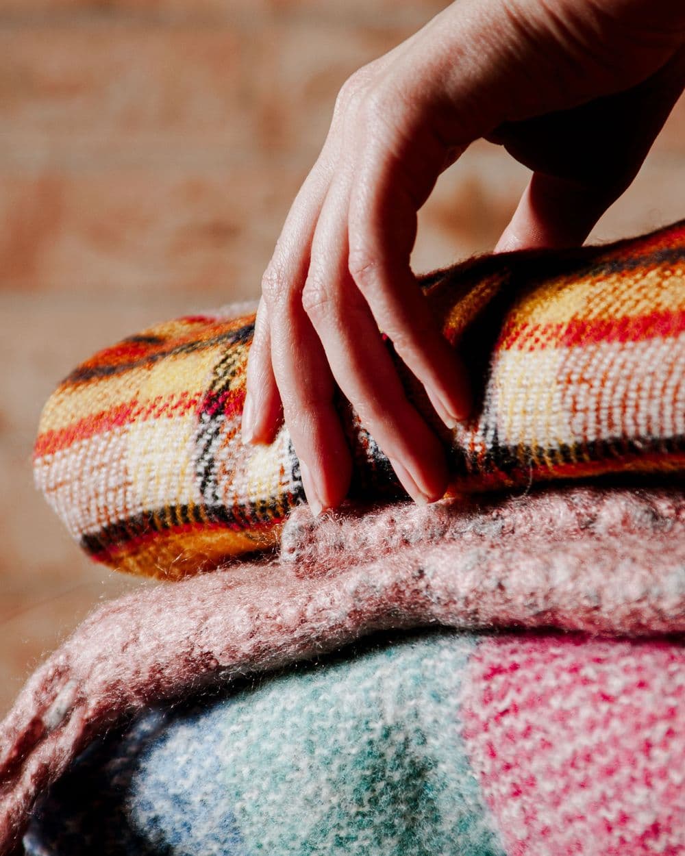 Hand resting on a stack of folded plaid wool blankets