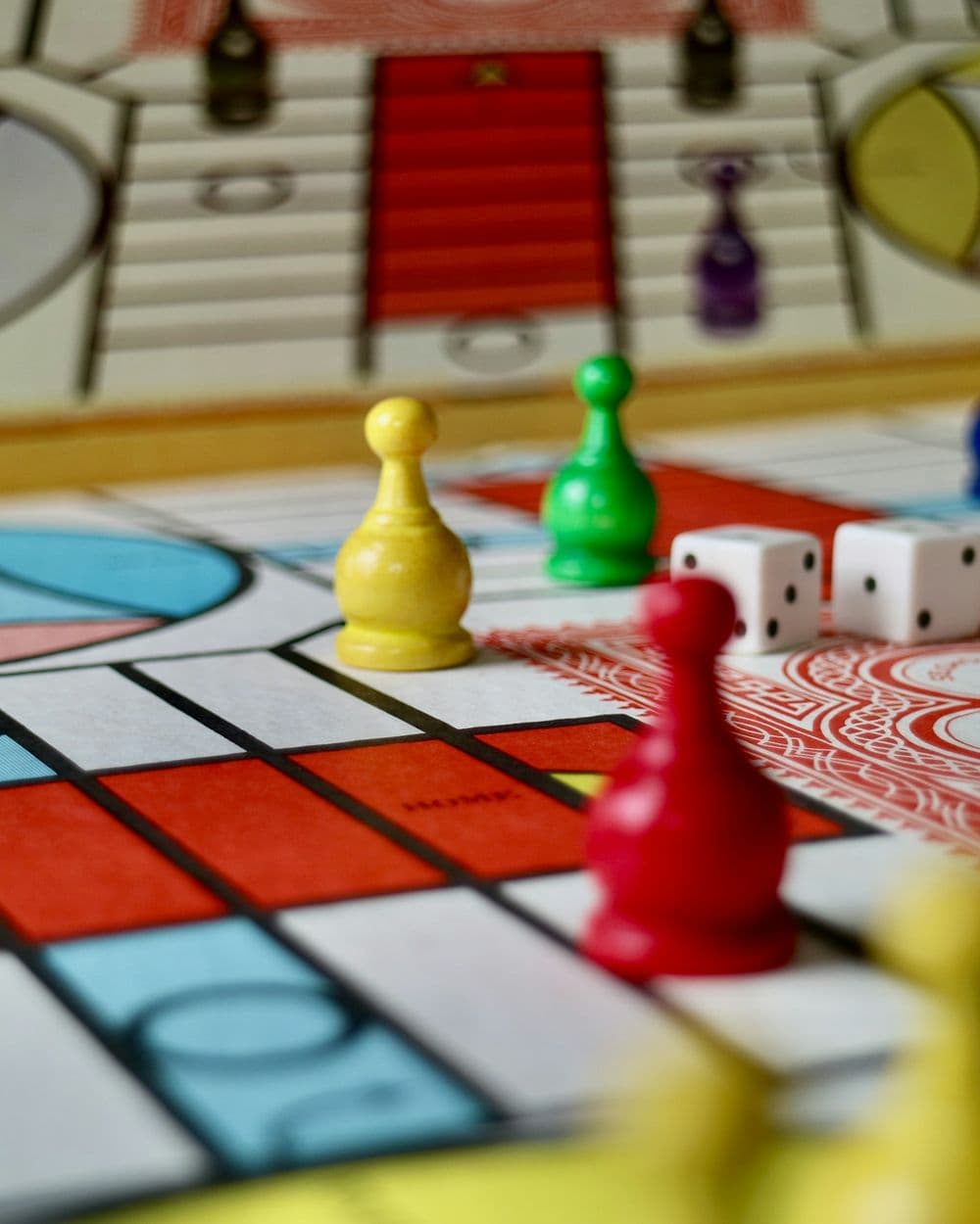 Colorful pawns and two white dice on a red, white and blue game board