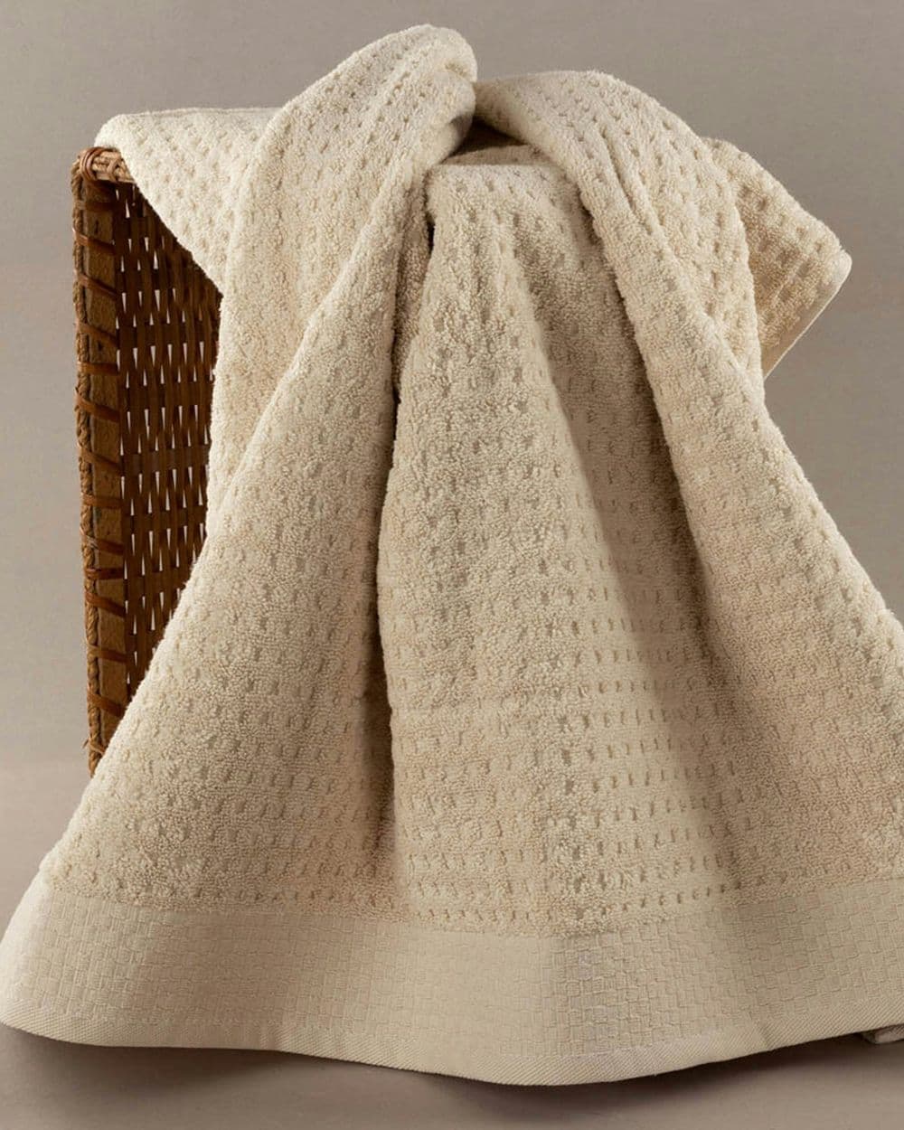 Cream waffle-weave cotton blanket draped over a wicker basket