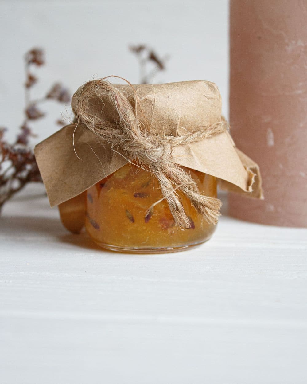 Jar of homemade peach jam topped with kraft paper and twine